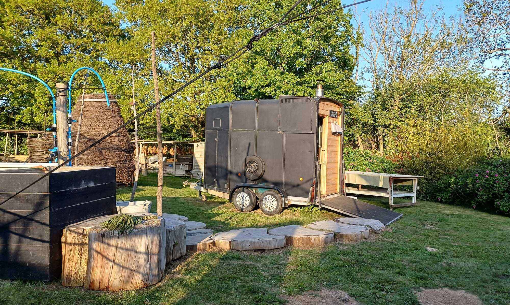 The LogJam Sauna horse-box trailer exterior with wooden door, East Sussex woodland