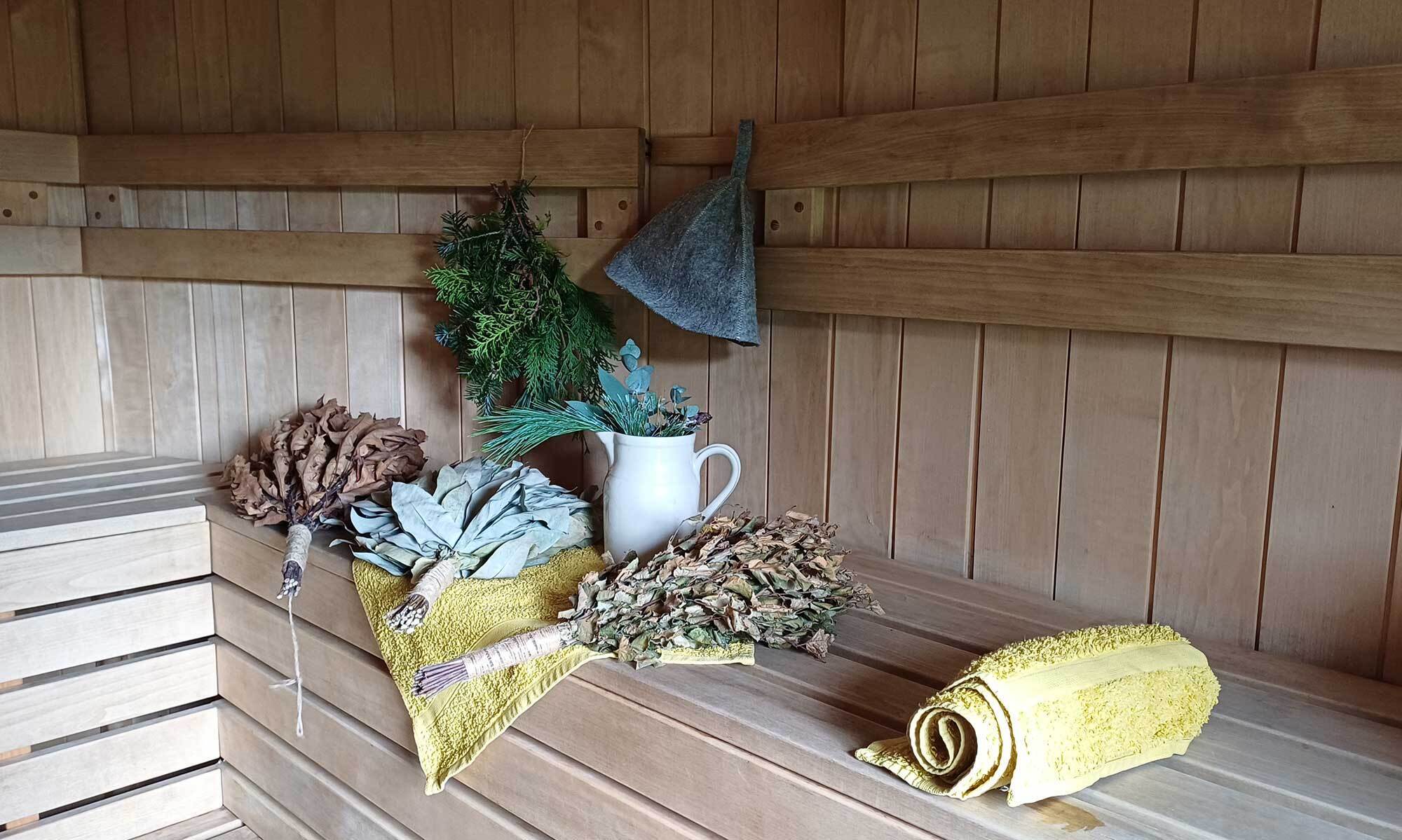 Interior of the LogJam Sauna with wooden benches, hanging herbs and a felt sauna hat